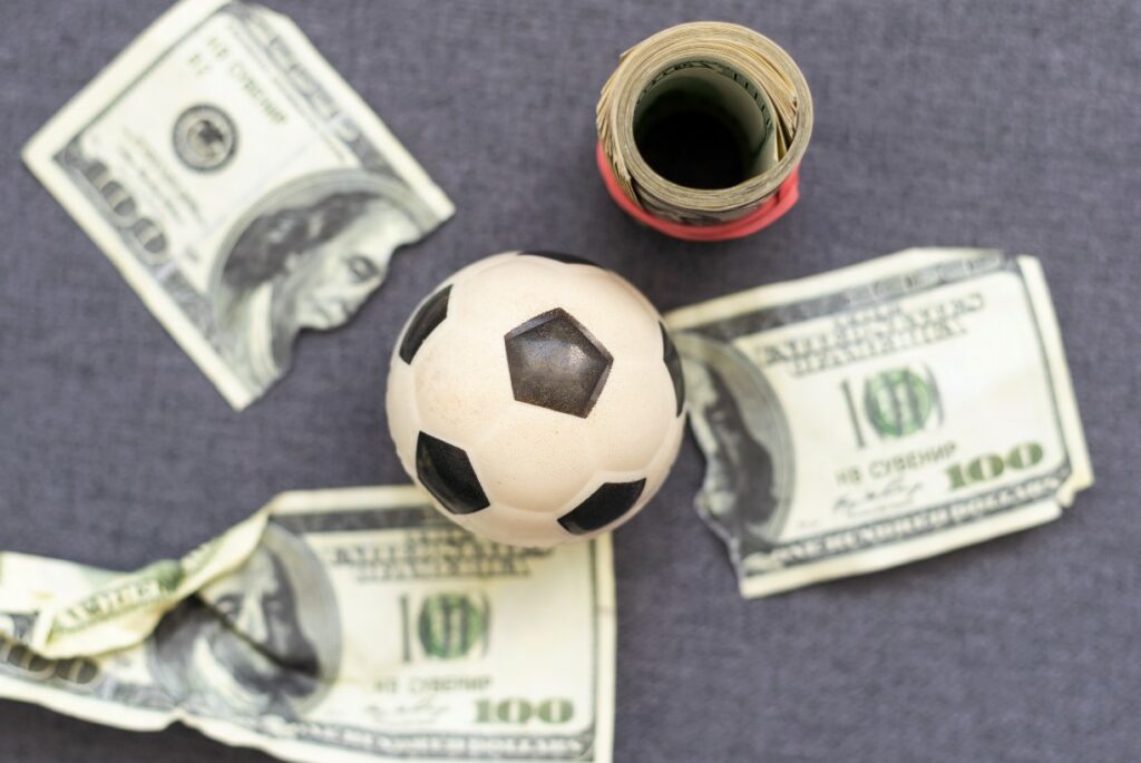 Toy soccer ball amid US currency indicative of Wisconsin Gov. Evers spending ARPA funds on building projects